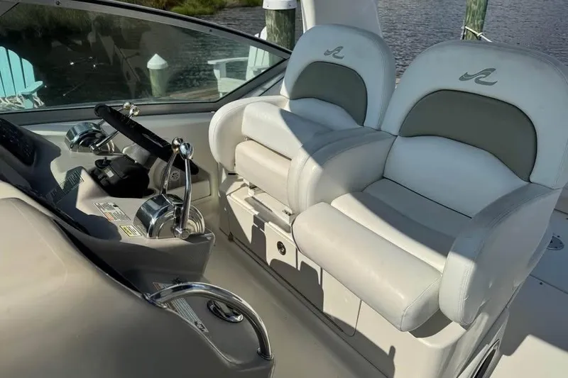 Slide: The Image of 2006 Sea Ray 340 Sundancer boat interior with white seating and helm, docked by the water. - 4