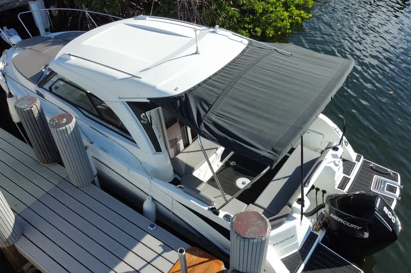 Slide: The Image of 2022 Beneteau Antares 8 docked, featuring a Mercury outboard motor and shaded canopy. - 10