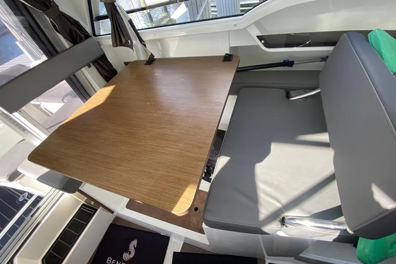 Slide: The Image of Interior of 2022 Beneteau Antares 8 with wooden table and gray seating. - 29