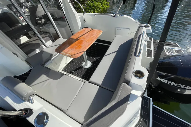 Slide: The Image of 2022 Beneteau Antares 8 boat interior with seating and wooden table, docked by water. - 37