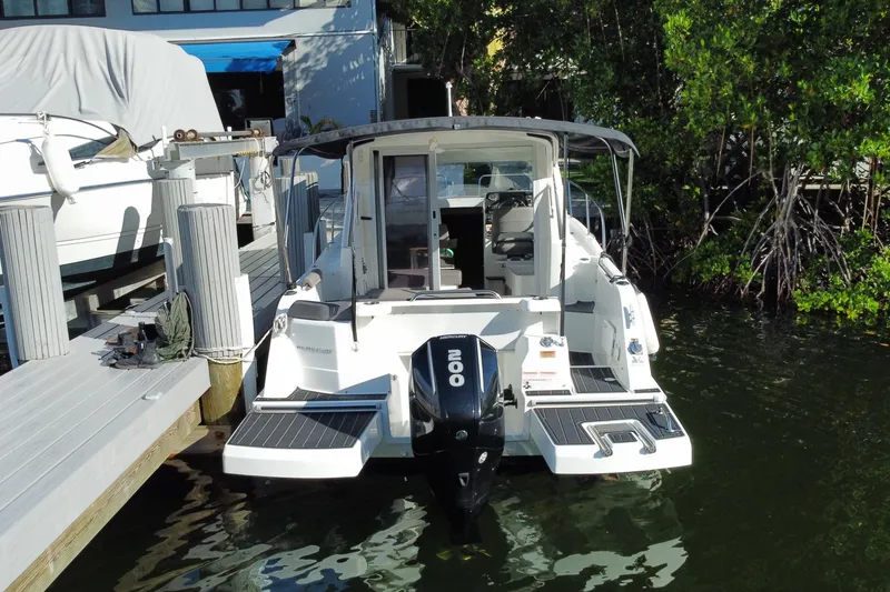Slide: The Image of 2022 Beneteau Antares 8 docked, rear view with outboard motor, surrounded by greenery. - 50