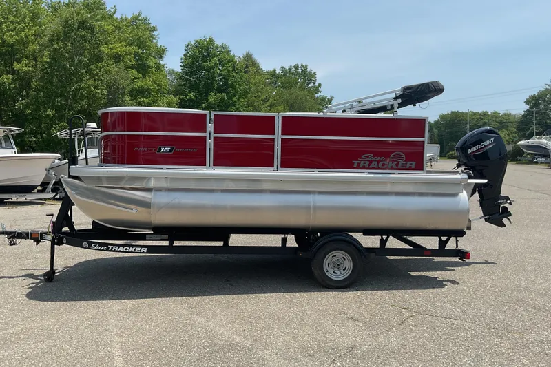 Slide: The Image of 2026 Sun Tracker Party Barge 16 DLX pontoon boat on trailer, parked outdoors. - 6