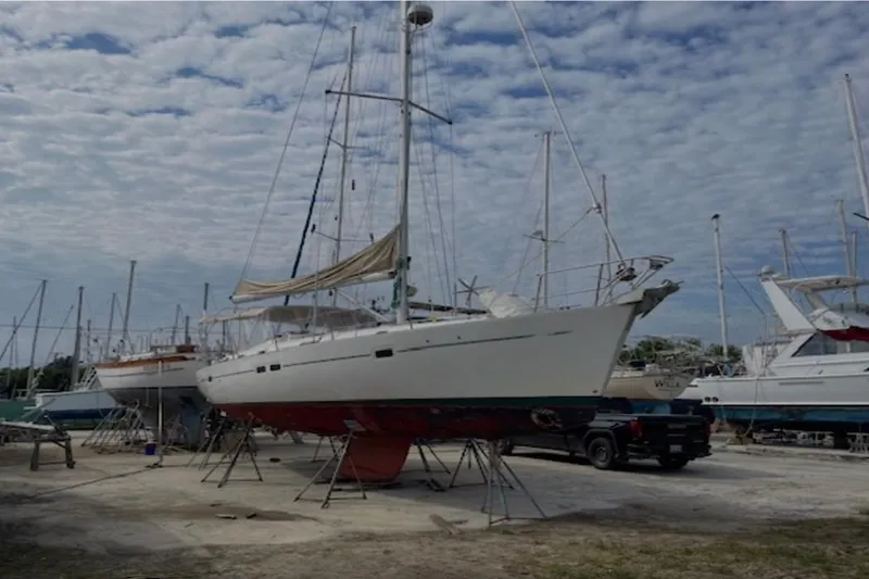 The Image of 2001 Beneteau Oceanis 411 sailboat on dry dock under cloudy sky. - 0