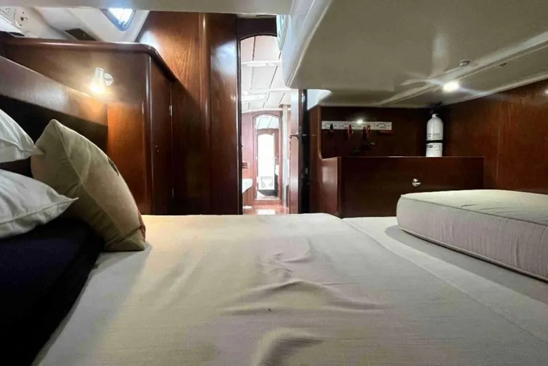 Slide: The Image of Interior cabin of 2001 Beneteau Oceanis 411 yacht, featuring cozy bedding and wooden finishes. - 10
