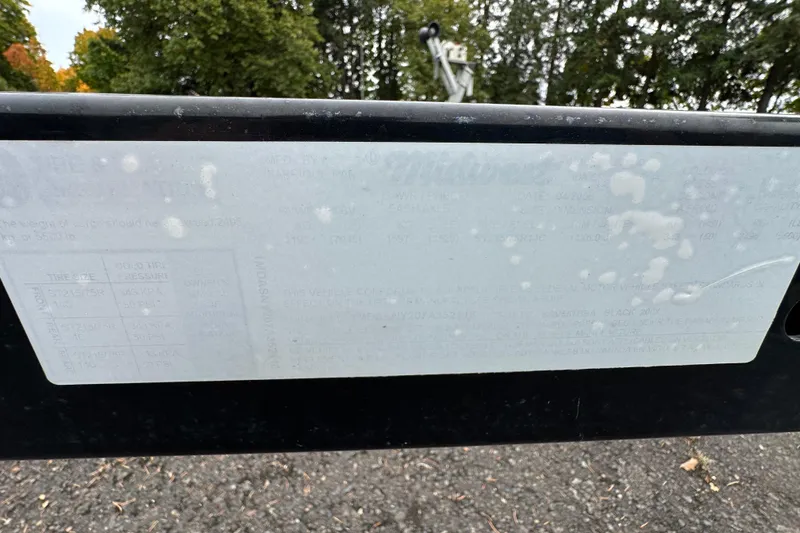 Slide: The Image of 2007 Sea Ray 225 Weekender label with faded text, outdoors with trees in background. - 32