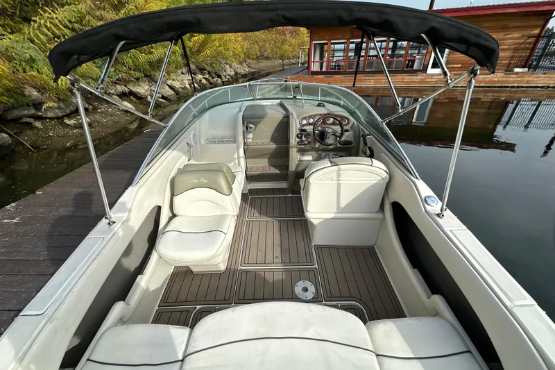 Slide: The Image of 2007 Sea Ray 225 Weekender boat interior with canopy, docked by a wooden pier. - 8