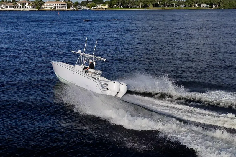 Slide: The Image of A 2005 Jupiter 27 boat speeding on a calm lake with scenic shoreline. - 12