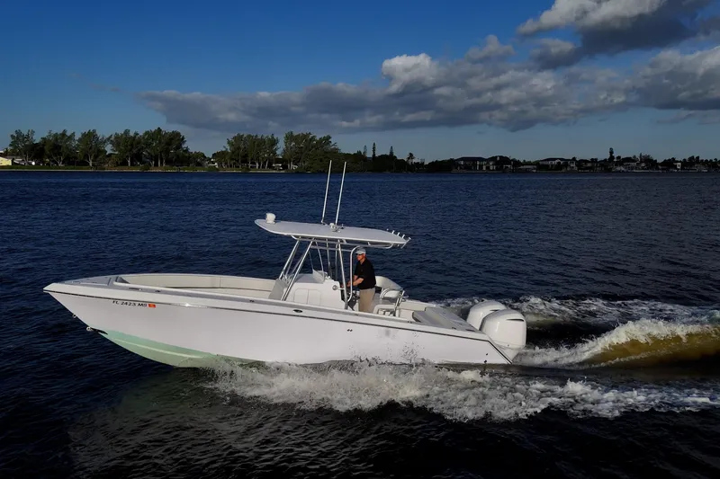 Slide: The Image of 2005 Jupiter 27 boat cruising on a scenic waterway under a partly cloudy sky. - 15
