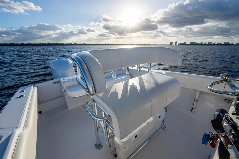 Slide: The Image of Jupiter 27 boat interior with white seating, ocean view, and city skyline at sunset. - 33