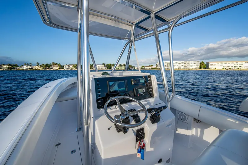 Slide: The Image of Cockpit view of 2005 Jupiter 27 boat on calm waters, showcasing steering and controls. - 36