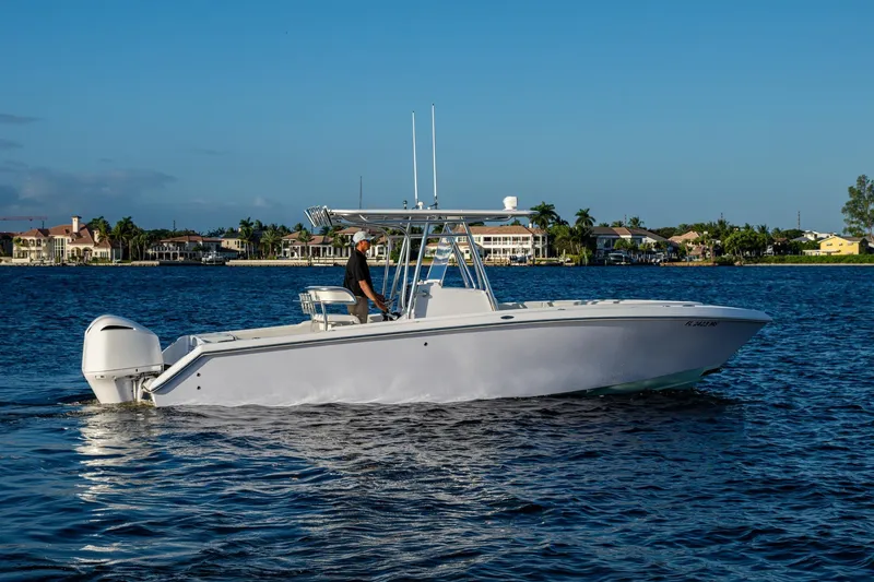 Slide: The Image of 2005 Jupiter 27 boat cruising on a calm lake with waterfront homes in the background. - 42