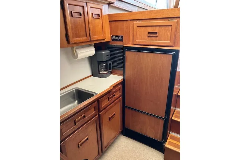 Slide: The Image of 1979 Pacemaker 40 Sportfisher kitchen with wooden cabinets, sink, and refrigerator. - 11