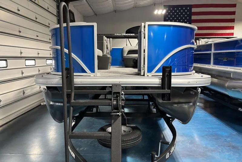 Slide: The Image of 2026 Sun Tracker Party Barge 16 DLX pontoon boat in showroom with American flag. - 8
