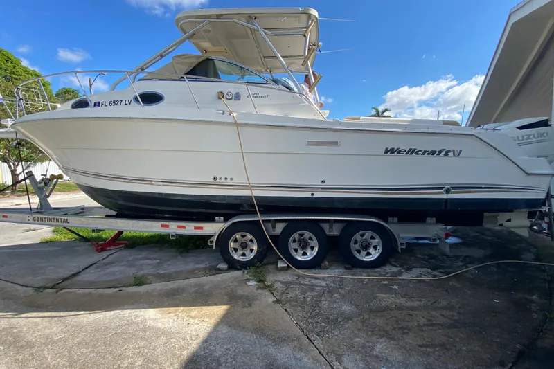 Slide: The Image of 2002 Wellcraft 290 Coastal boat on trailer, parked outdoors under clear blue sky. - 12