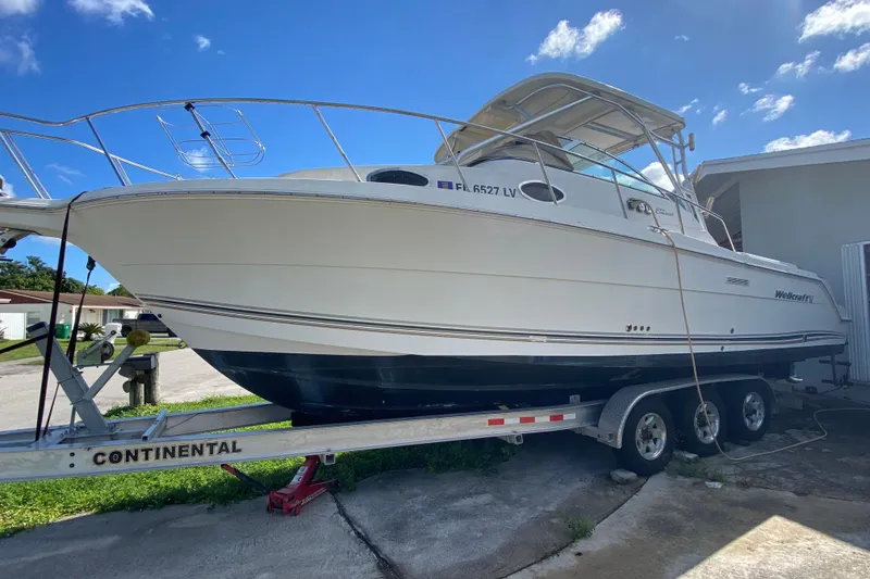 Slide: The Image of 2002 Wellcraft 290 Coastal boat on trailer under clear blue sky. - 14