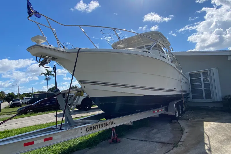 Slide: The Image of 2002 Wellcraft 290 Coastal boat on trailer under a clear blue sky. - 37