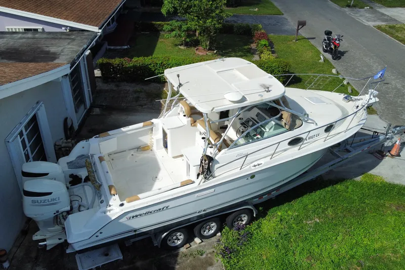 Slide: The Image of 2002 Wellcraft 290 Coastal boat on trailer, parked beside a house, with Suzuki engines. - 4