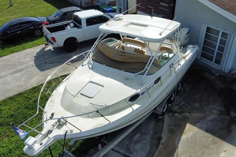 Slide: The Image of 2002 Wellcraft 290 Coastal boat on trailer, parked beside a house and vehicles. - 8