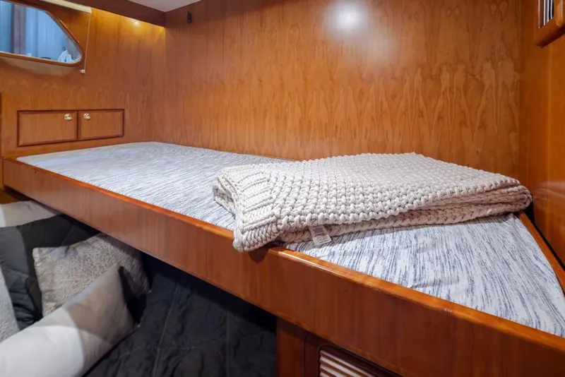 Slide: The Image of Cozy cabin interior of 2004 Mikelson 50 Sportfisher with wooden finish and bedding. - 18