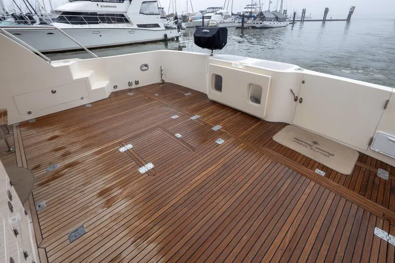 Slide: The Image of 2004 Mikelson 50 Sportfisher yacht deck with wooden flooring, docked at marina. - 38