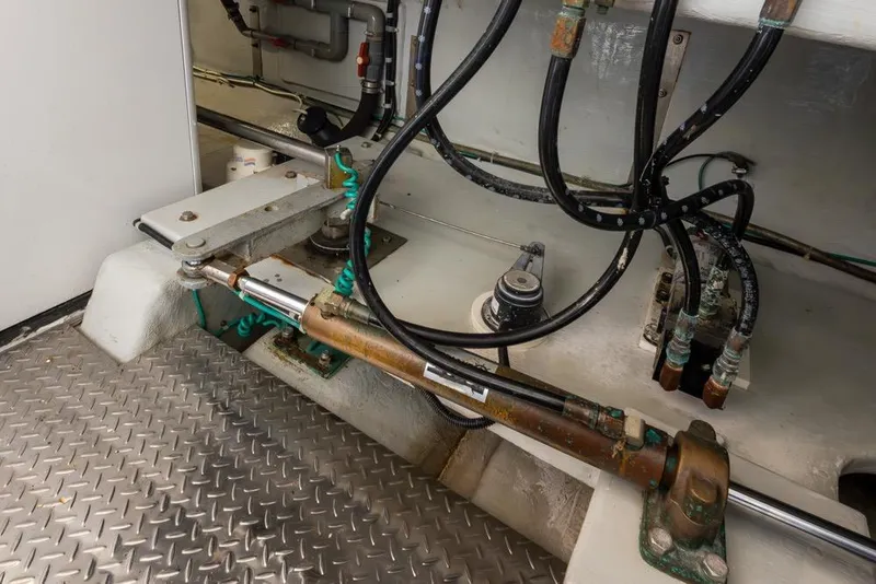 Slide: The Image of Engine room of 2004 Mikelson 50 Sportfisher with hydraulic components and metal flooring. - 49