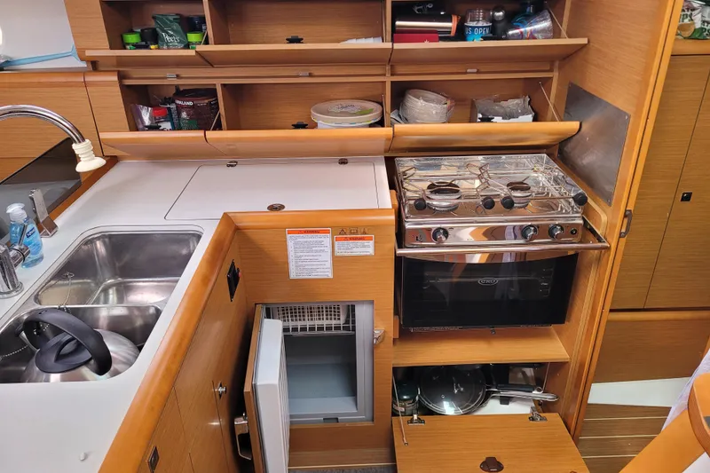 Slide: The Image of 2014 Jeanneau 379 yacht kitchen with stove, sink, and storage cabinets. - 59