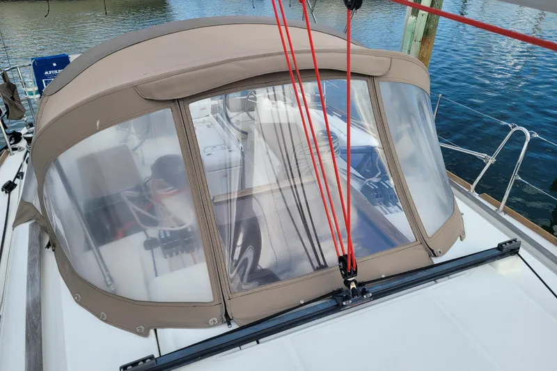 Slide: The Image of 2014 Jeanneau 379 sailboat with tan cockpit enclosure, docked by the water. - 18
