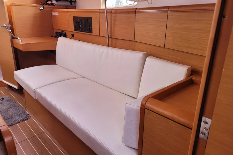 Slide: The Image of Interior of 2014 Jeanneau 379 sailboat with white cushioned seating and wooden paneling. - 31