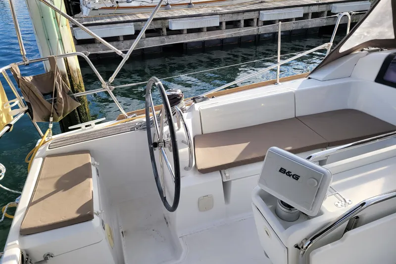 Slide: The Image of 2014 Jeanneau 379 sailboat cockpit with seating and steering wheel, docked at marina. - 6
