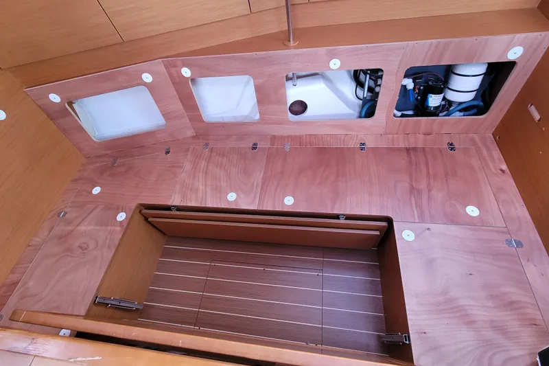 Slide: The Image of Interior view of 2014 Jeanneau 379 sailboat, showcasing wooden storage compartments and access panels. - 61