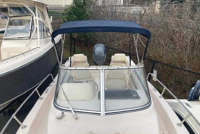 Slide: The Image of 2012 Grady-White Adventure 208 boat with blue canopy, docked alongside another vessel. - 12