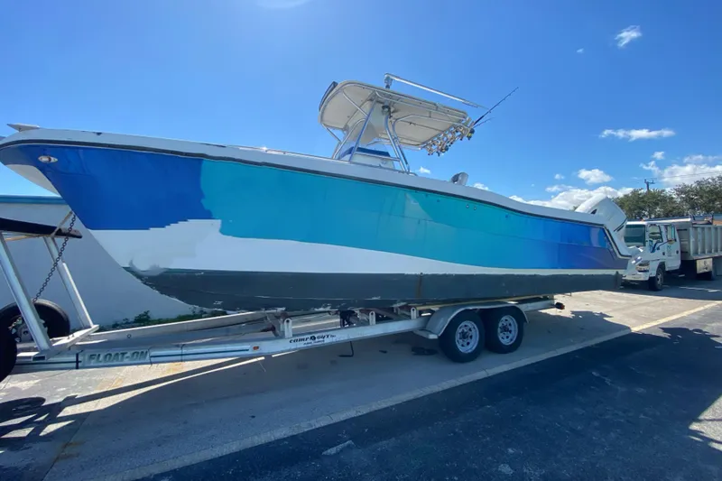 Slide: The Image of 2002 ProKat 2660 Center Console boat on trailer under clear blue sky. - 2