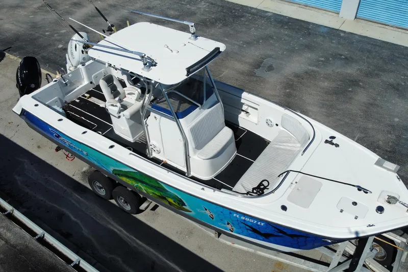 Slide: The Image of 2002 ProKat 2660 Center Console boat with vibrant marine graphics, parked on a trailer. - 29