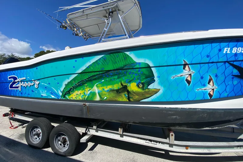 Slide: The Image of 2002 ProKat 2660 Center Console boat with vibrant fish-themed hull artwork on a trailer. - 61