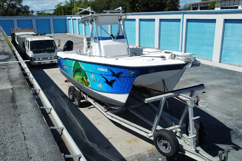 Slide: The Image of 2002 ProKat 2660 Center Console boat on trailer, vibrant marine graphics, storage facility background. - 7