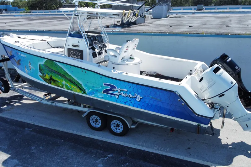 Slide: The Image of 2002 ProKat 2660 Center Console boat with vibrant marine graphics on a trailer. - 8