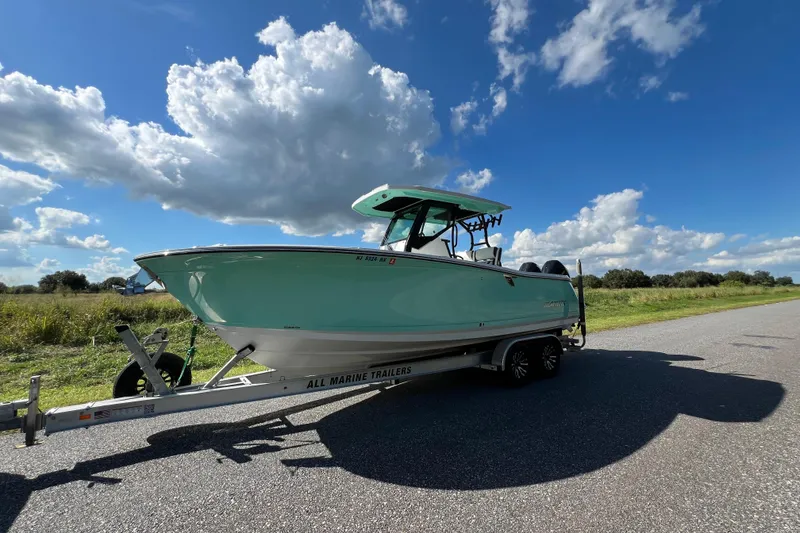 Slide: The Image of 2023 Blackfin 272 boat on trailer under a bright blue sky. - 1