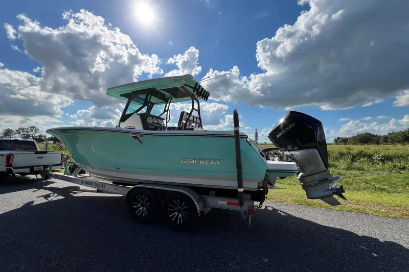 Slide: The Image of 2023 Blackfin 272 boat on trailer under sunny sky, featuring Mercury outboard engine. - 25