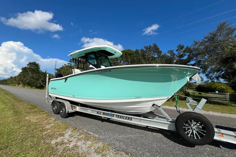 Slide: The Image of 2023 Blackfin 272 boat on trailer, parked on roadside under clear blue sky. - 26