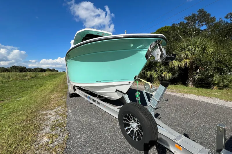 Slide: The Image of 2023 Blackfin 272 boat on trailer, parked on a rural road under a clear blue sky. - 28