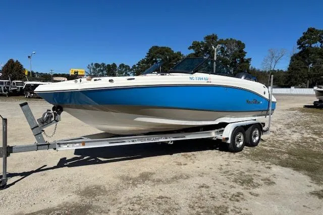 The Image of 2016 NauticStar 223 DC boat on trailer, blue and white design, parked outdoors. - 1