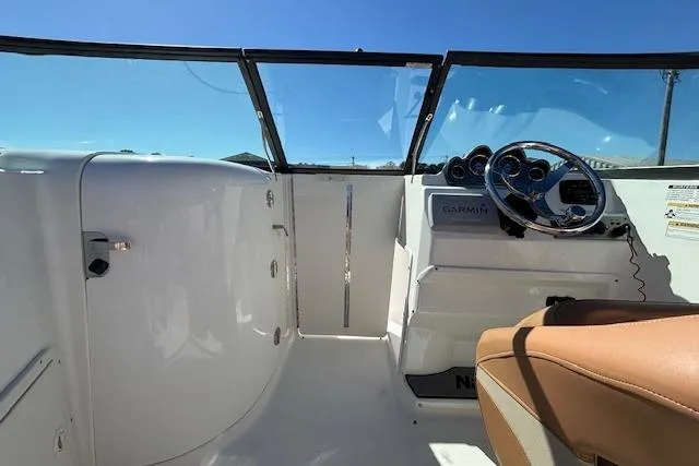 Slide: The Image of 2016 NauticStar 223 DC boat interior with steering wheel and dashboard under clear blue sky. - 18