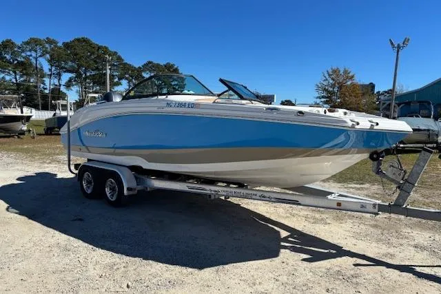 Slide: The Image of 2016 NauticStar 223 DC boat on trailer, parked outdoors under clear blue sky. - 3