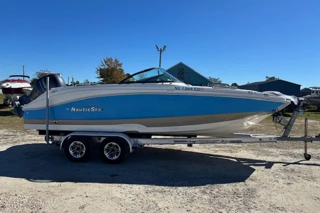 Slide: The Image of 2016 NauticStar 223 DC boat on trailer, blue and white design, parked outdoors. - 4