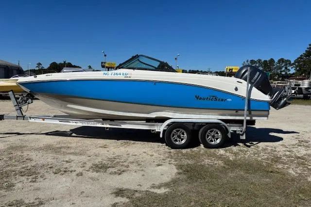 Slide: The Image of 2016 NauticStar 223 DC boat on trailer, blue and white design, parked outdoors. - 8