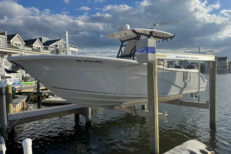Slide: The Image of 2023 Sea Fox 268 Commander boat on lift at marina, under cloudy sky. - 2