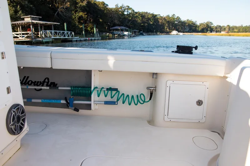 Slide: The Image of 2014 Yellowfin 34 Offshore boat interior with storage and hose, dockside view. - 31