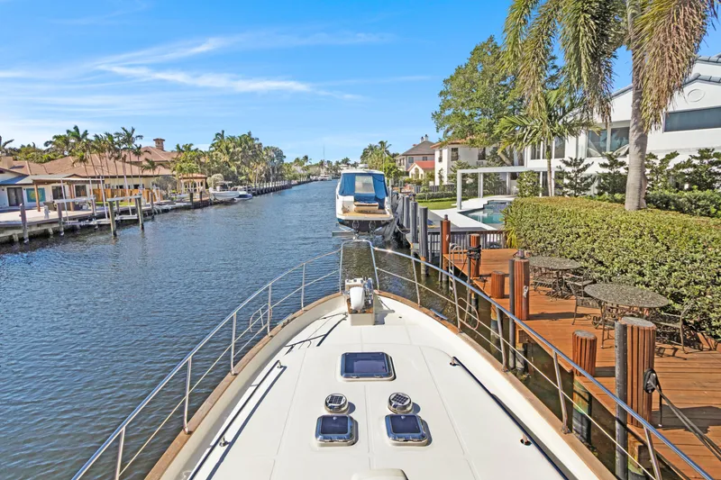 Slide: The Image of Luxury yacht cruising through a scenic canal, surrounded by waterfront homes and palm trees. - 54