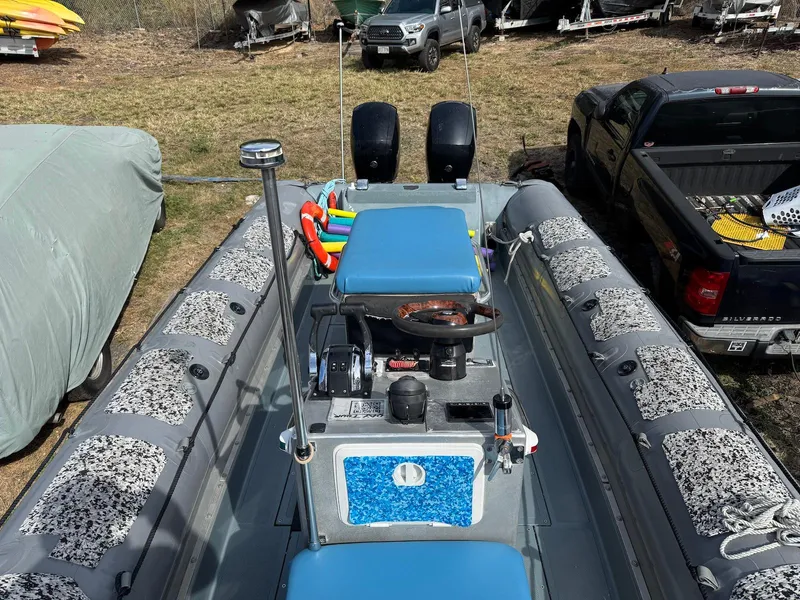 Slide: The Image of 2012 Zodiac 733 Hurricane boat with dual engines and blue seating, parked outdoors. - 11
