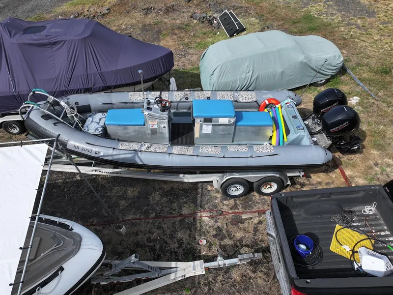 Slide: The Image of Zodiac 733 Hurricane 2012 inflatable boat on trailer, parked outdoors with covered vehicles nearby. - 5